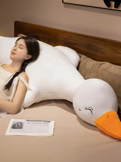 Woman lying on a bed with a large duck plushie body pillow
