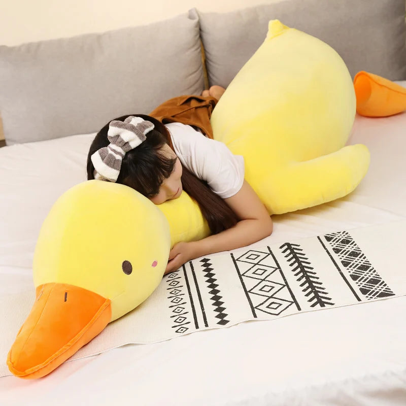 Person lying on a couch with large yellow duck plushie pillow