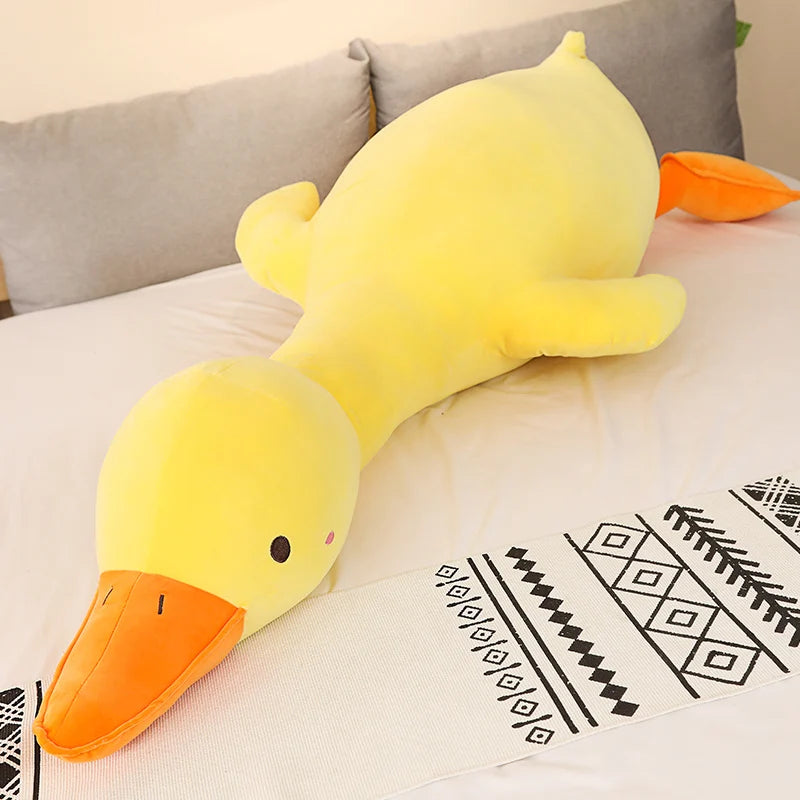 Yellow duck-shaped plush toy on a couch with a patterned blanket