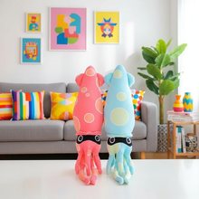 Colorful squid-shaped plush toys in a living room setting with abstract art and decor.