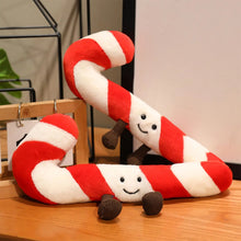 Red and white striped candy cane plush toy with a smiling face on a wooden surface.