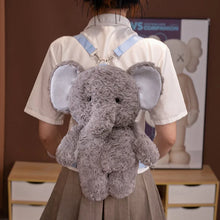 Person wearing a plush elephant backpack in a room with a poster on the wall.