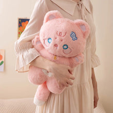 Person holding a pink plush toy with cartoon cat face design against a neutral background