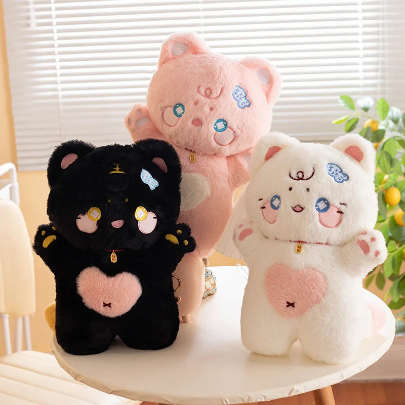 Three colorful cat plush toys (black, pink, and white) on a table with a light background.