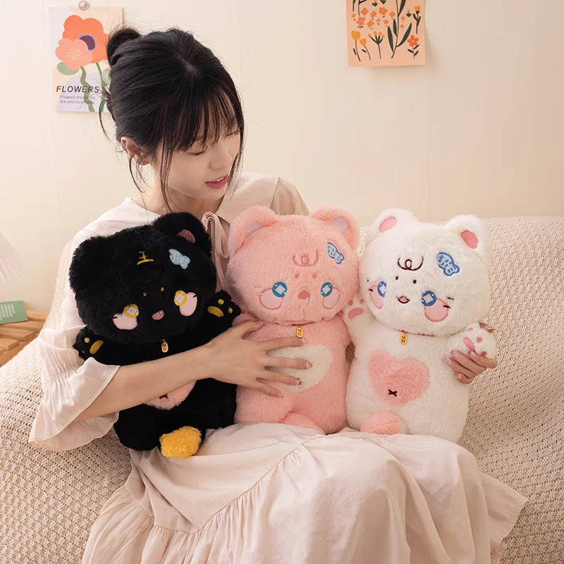 Woman holding three cat plush toys on a couch with a light-colored wall and floral decorations in the background.