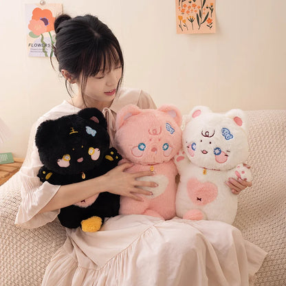 Woman holding three cat plush toys on a couch with a light-colored wall and floral decorations in the background.