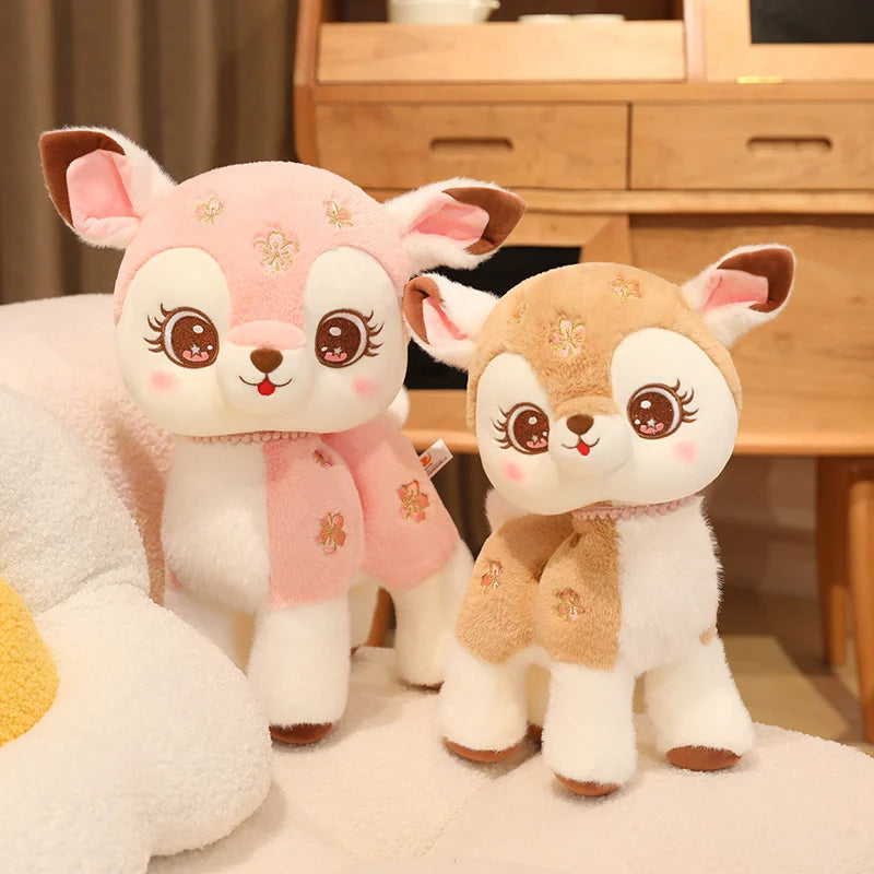 Two cute plush deer toys on a soft surface with a wooden cabinet in the background.