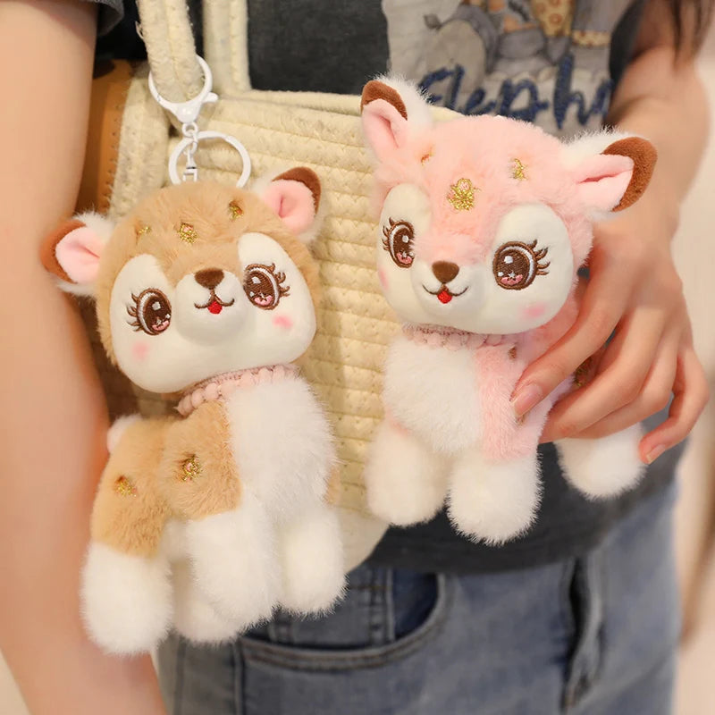 Two plush reindeer animal keychains held by a person against a neutral background