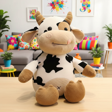 Plush cow toy on a wooden table with a colorful living room background
