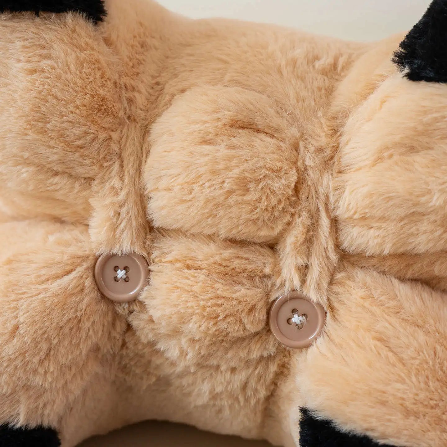 Close-up of a plush toy with button details on a beige background