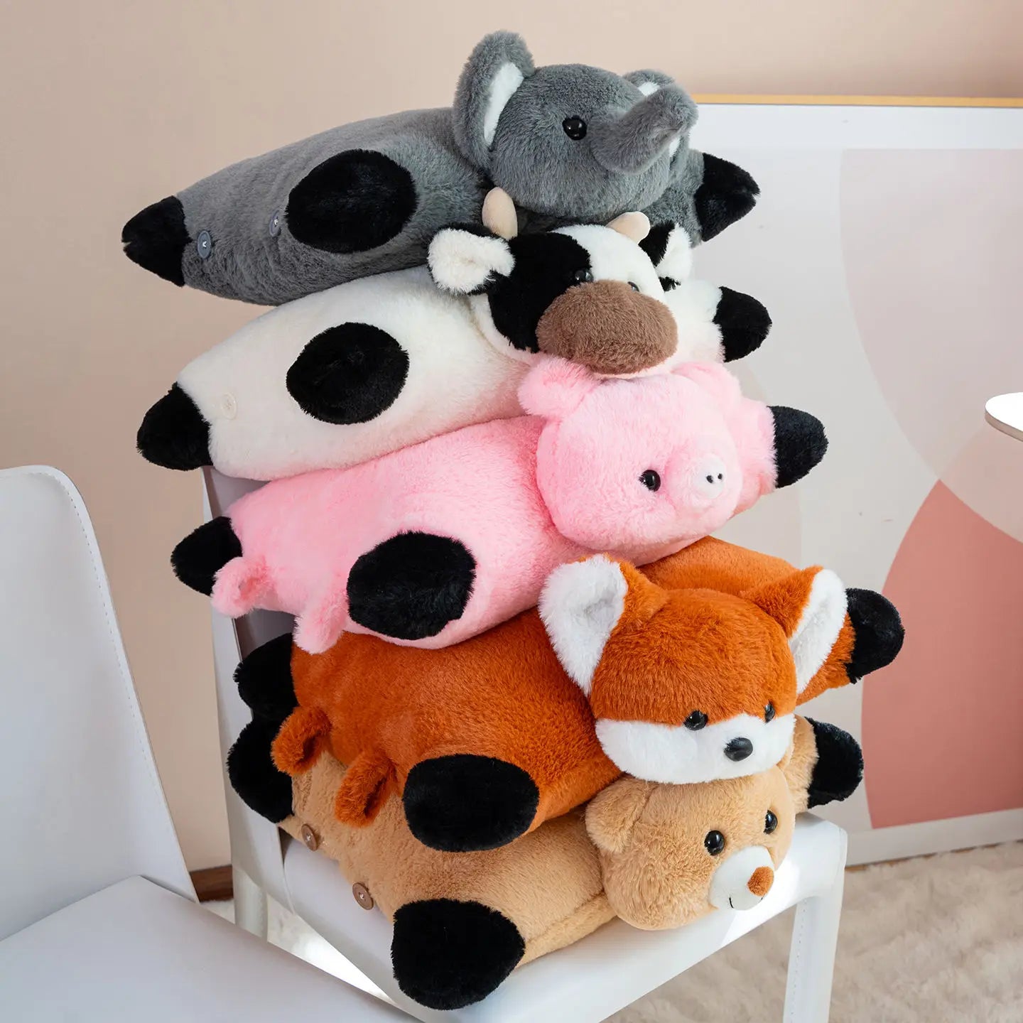 Stack of plush toys including a cow, elephant, pig, and fox on a white chair.