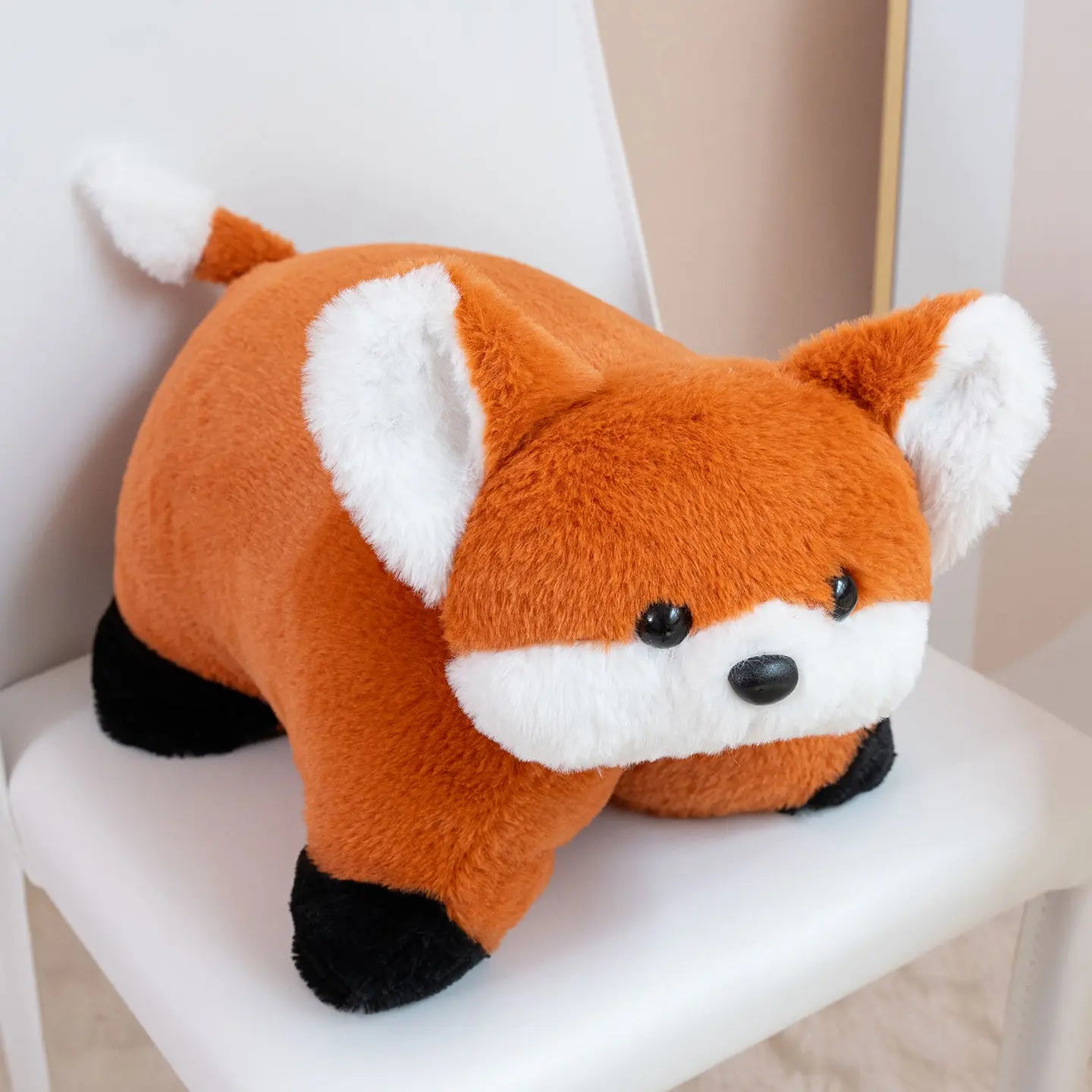 Plush toy fox sitting on a white chair