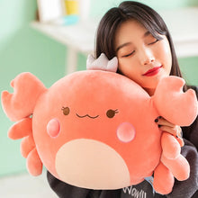 Person holding a large, plush, cartoon-like crab plush toy against a blurred indoor background