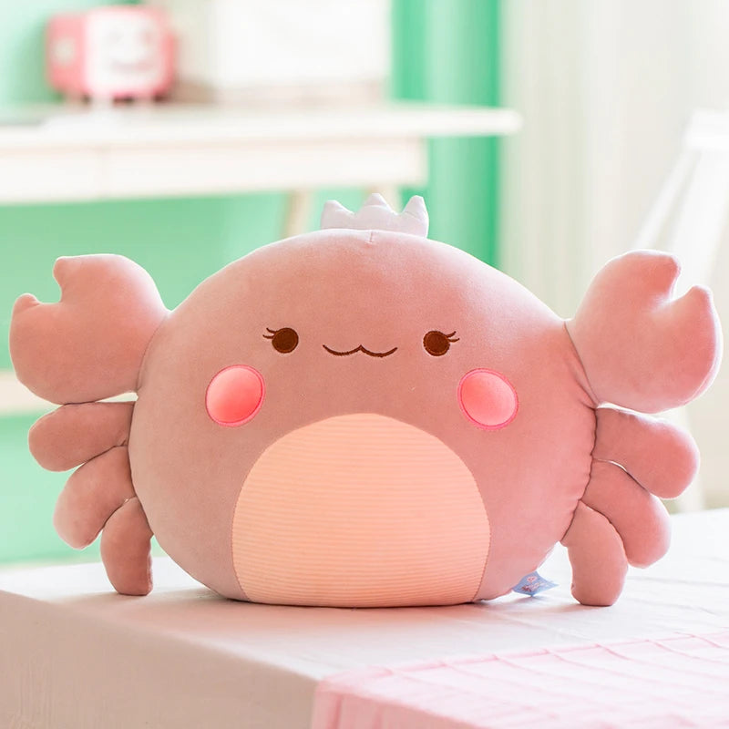 Cute pink/gray crab plush toy on a light surface with a blurred background