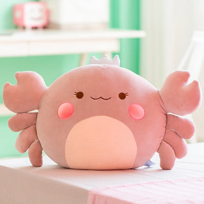 Cute pink/gray crab plush toy on a light surface with a blurred background