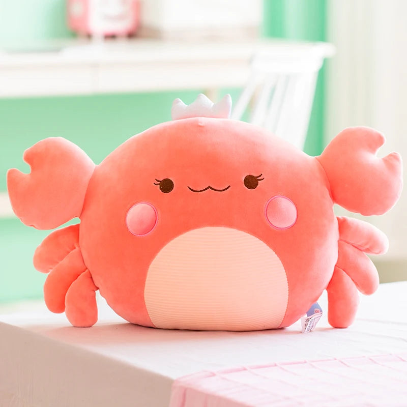 Cute pink crab plush toy on a white surface with a blurred background