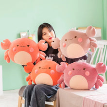 Person sitting with four large, colorful crab-shaped plush toys against a light green wall.