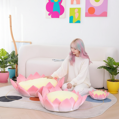 Person sitting on a white couch with pink and yellow lotus-shaped plush cushions in a bright room.