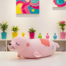 Pink plush toy resembling a seal on a table with a colorful background