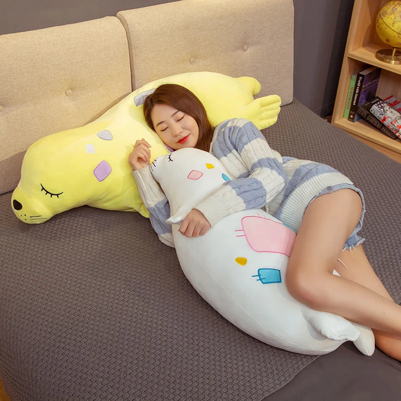 Person lying on a bed with large, colorful animal-shaped sea lion plush body pillows
