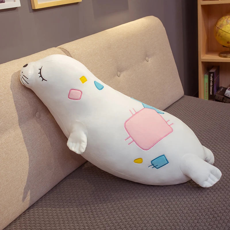 White Kawaii Sea Lion Plushie with colorful designs on a bed