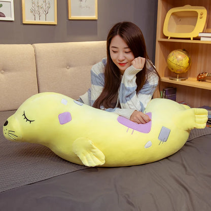 Woman sitting on a bed with a large yellow plush toy resembling a Kawaii Sea Lion Plushie