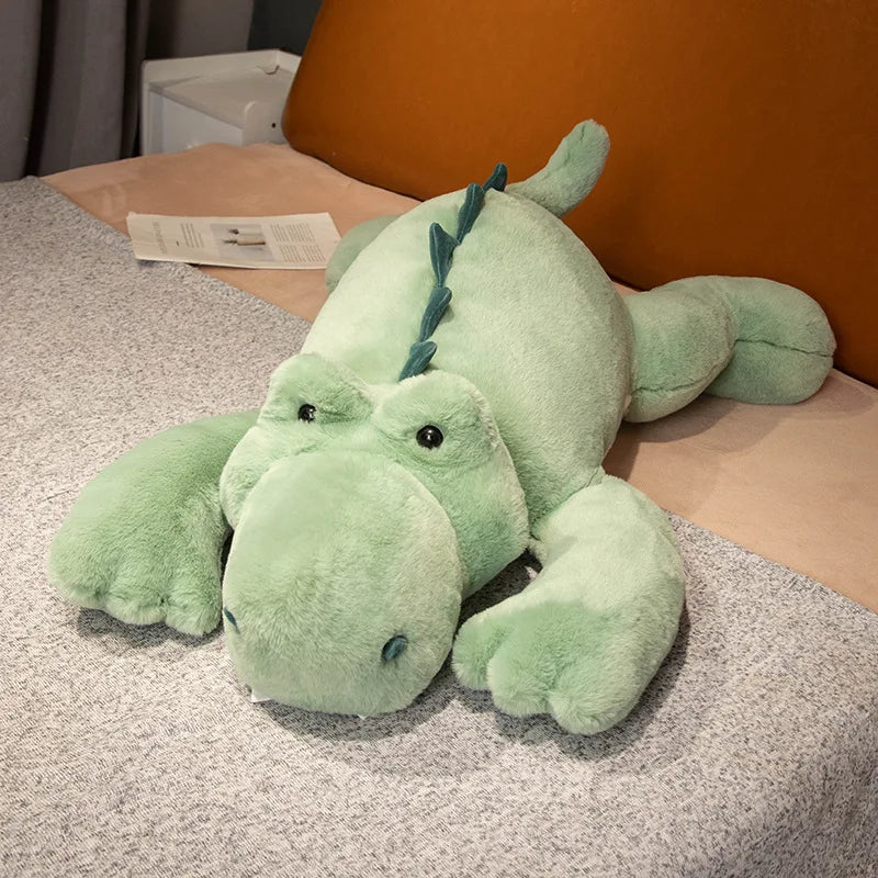 Green plush crocodile toy on a bed with a blurred background