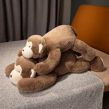 Stack of brown plush monkey toys on a gray surface with a chair in the background.