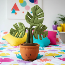 Plush toy plant with a smiling face on a colorful bedspread