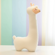 Plush toy alpaca against a pastel-colored curtain background