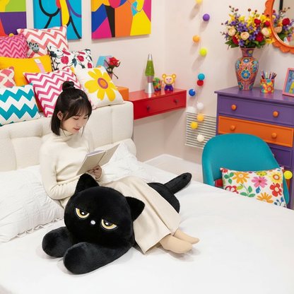 Woman sitting on a bed reading a book with a black cat stuffed animal as a pillow