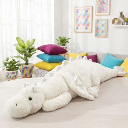 Large white dragon plush toy on a couch in a bright living room with colorful pillows and plants.