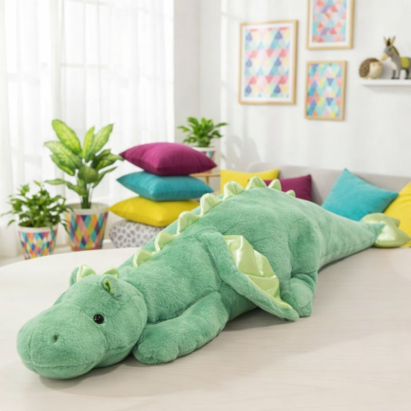 Large green plush dragon toy on a bed in a bright room with colorful pillows and plants.