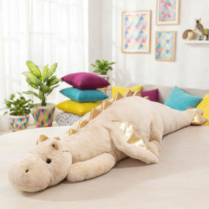 Large plush dragon toy on a sofa in a bright living room with colorful pillows and plants.