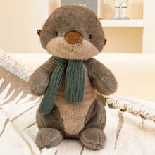Plush sea otter with a green scarf on a soft surface