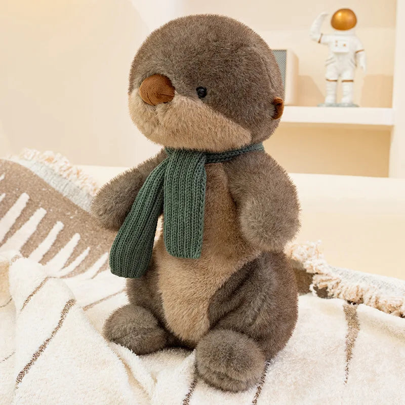 Plush toy otter wearing a green scarf on a soft surface