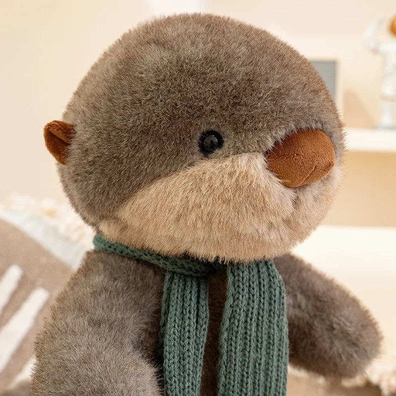 Plush otter toy wearing a green scarf on a neutral background