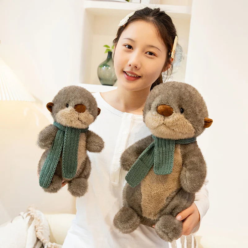Person holding two plush otters with scarves in a cozy indoor setting