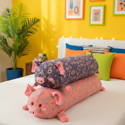 Two decorative body pillows shaped like pigs on a bed with a colorful wall and plant in the background.