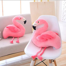 Two pink flamingo stuffed animals on a chair and a couch