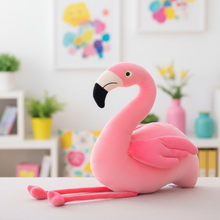 Pink plush flamingo plush toy on a table with a colorful blurred background