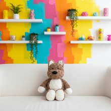 Plush toy dog on a white couch with a colorful geometric wall in the background
