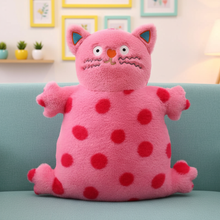 Pink plush cat with red polka dots on a light blue couch