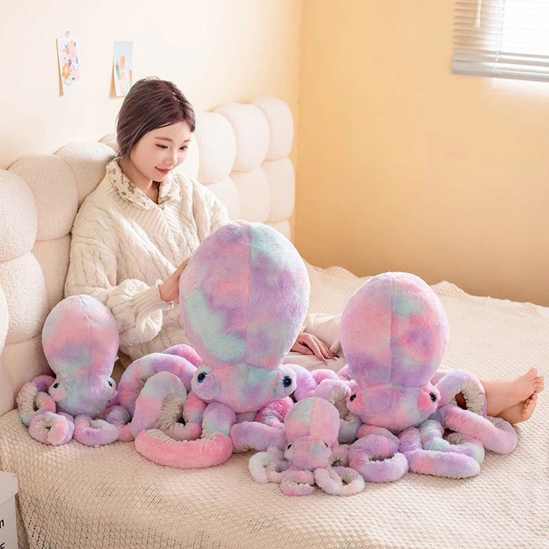 Woman sitting on a bed with a large number of colorful plush octopuses.