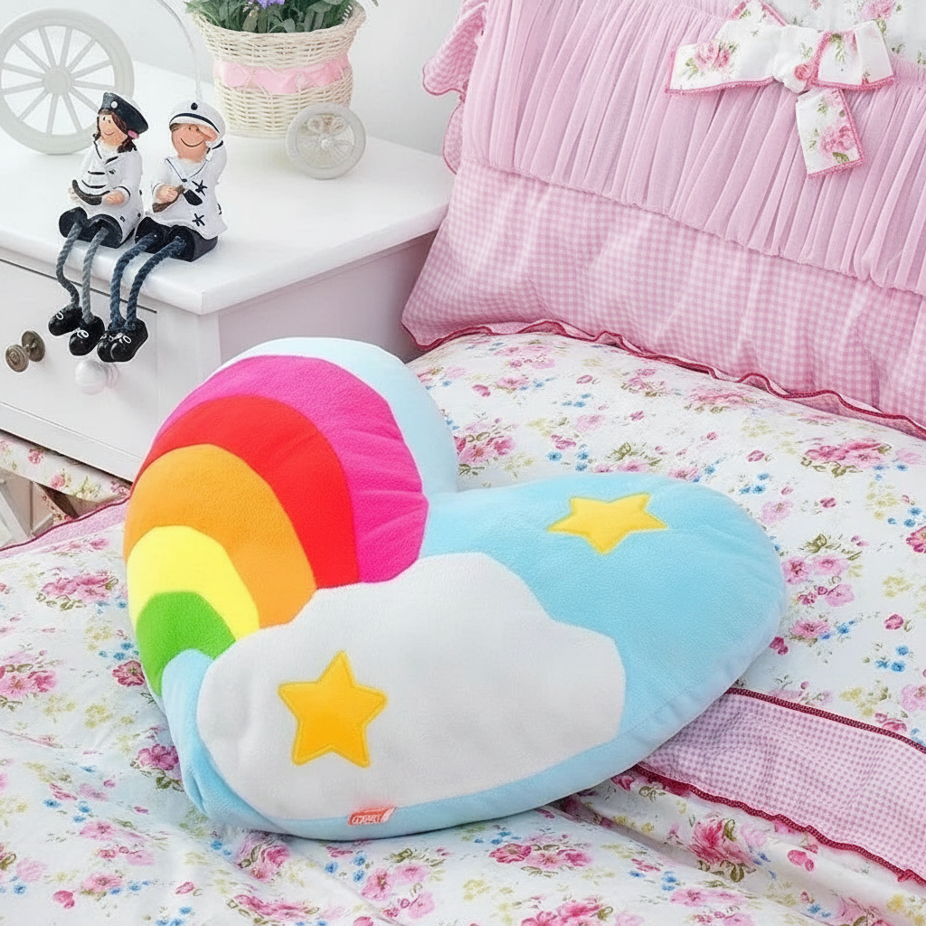Colorful cloud-shaped pillow with rainbow and stars on a bed with floral bedding.