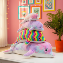 Stack of colorful dolphin plush toys in a room with pink walls and framed pictures.