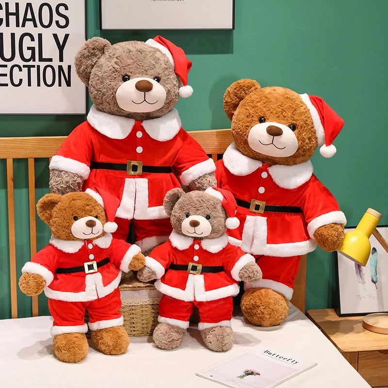 Set of teddy bears dressed in Santa Claus outfits on a bed with a green wall in the background.