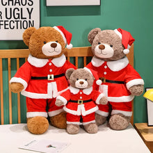 Three teddy bears dressed in Santa Claus outfits on a wooden bench against a green wall.