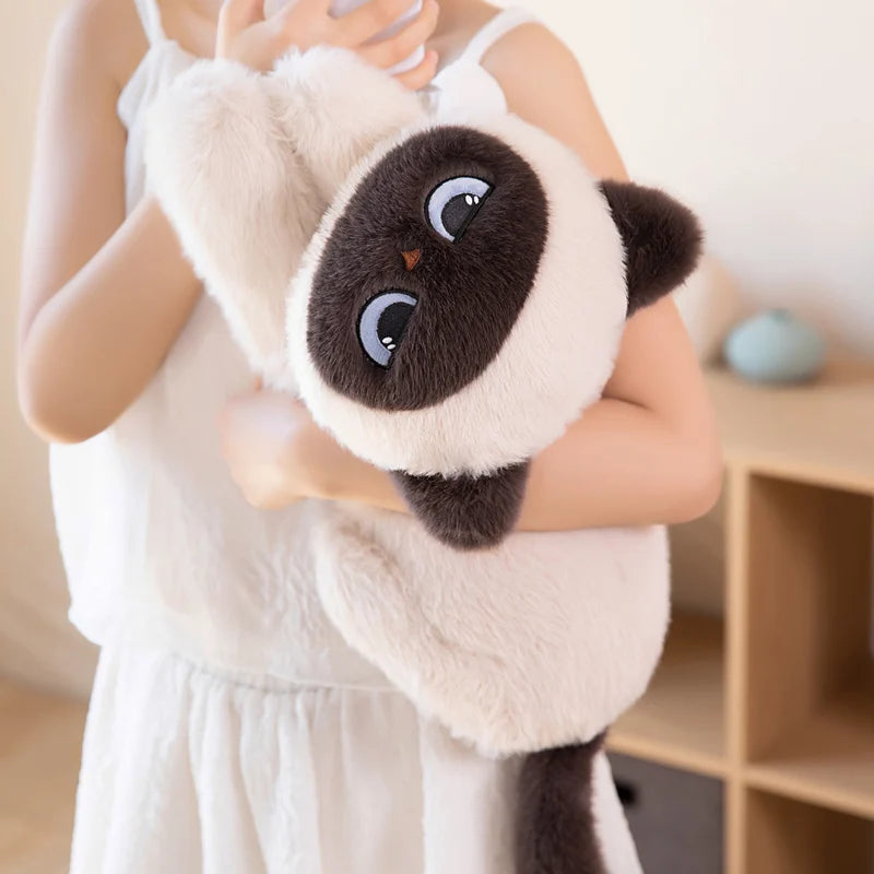 Person holding a plush cat with a sad face design.