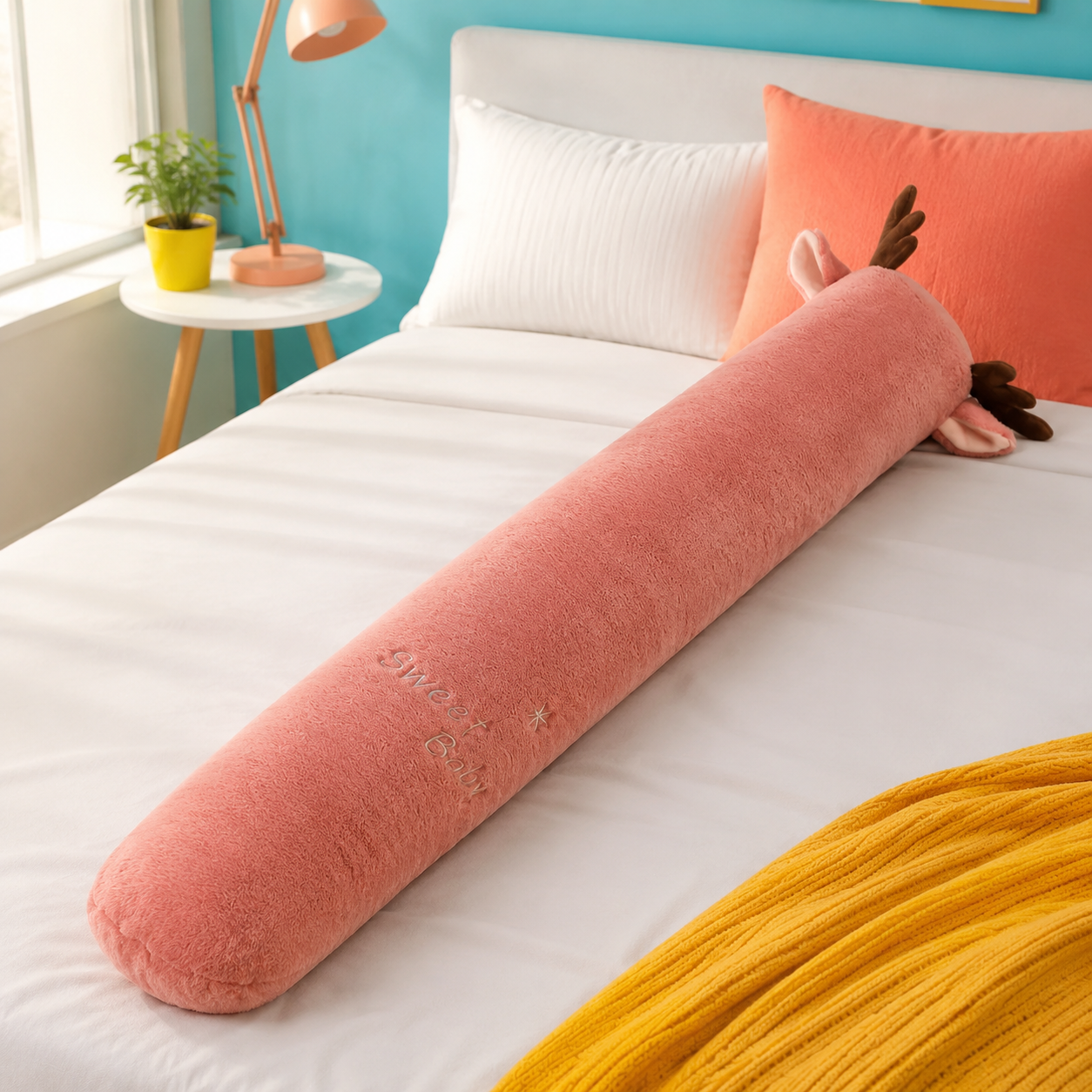 Dusty rose deer long plushie body pillow with brown antlers on a colorful bed